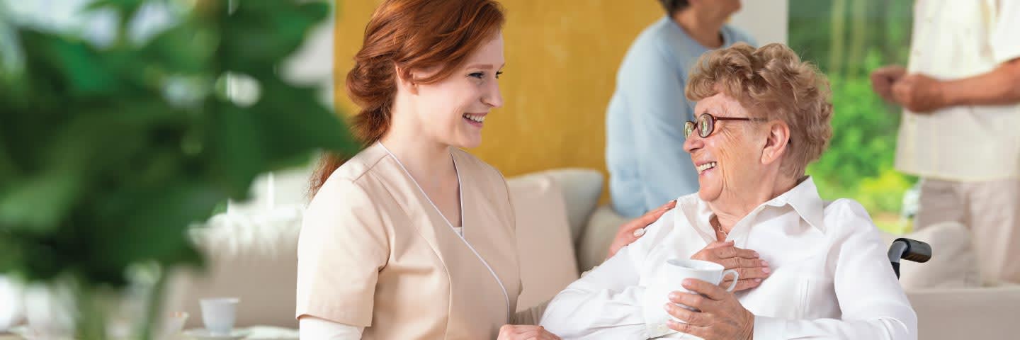 Senior and caregiver looking at each other smiling